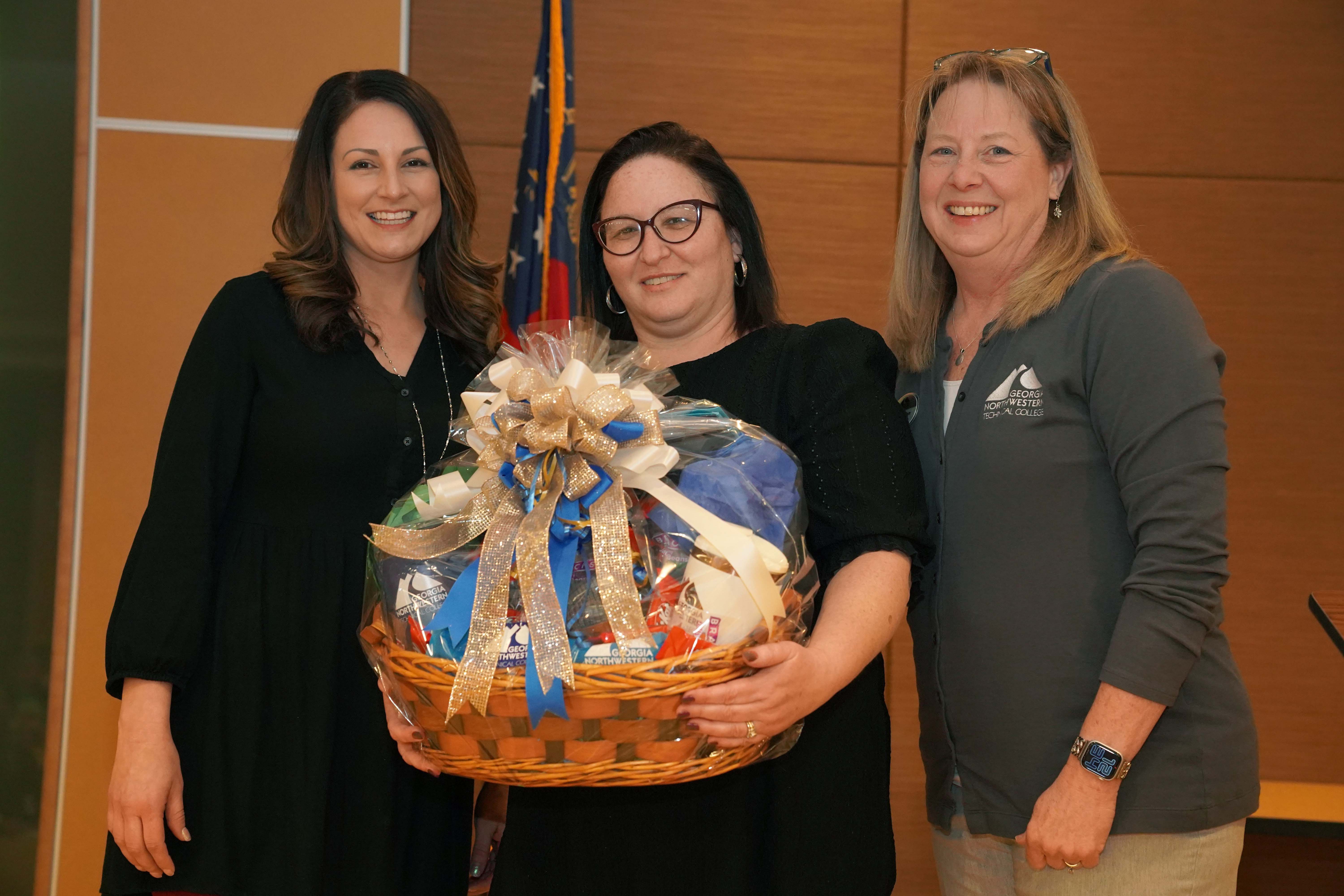 Elizabeth Barksdale, director of Human Resources at GNTC (left), and Dr. Heidi Popham, GNTC president (right), present Adi Baxter with a GNTC gift basket in recognition of her selection as GNTC’s 2025 Staff Member of the Year Award winner.