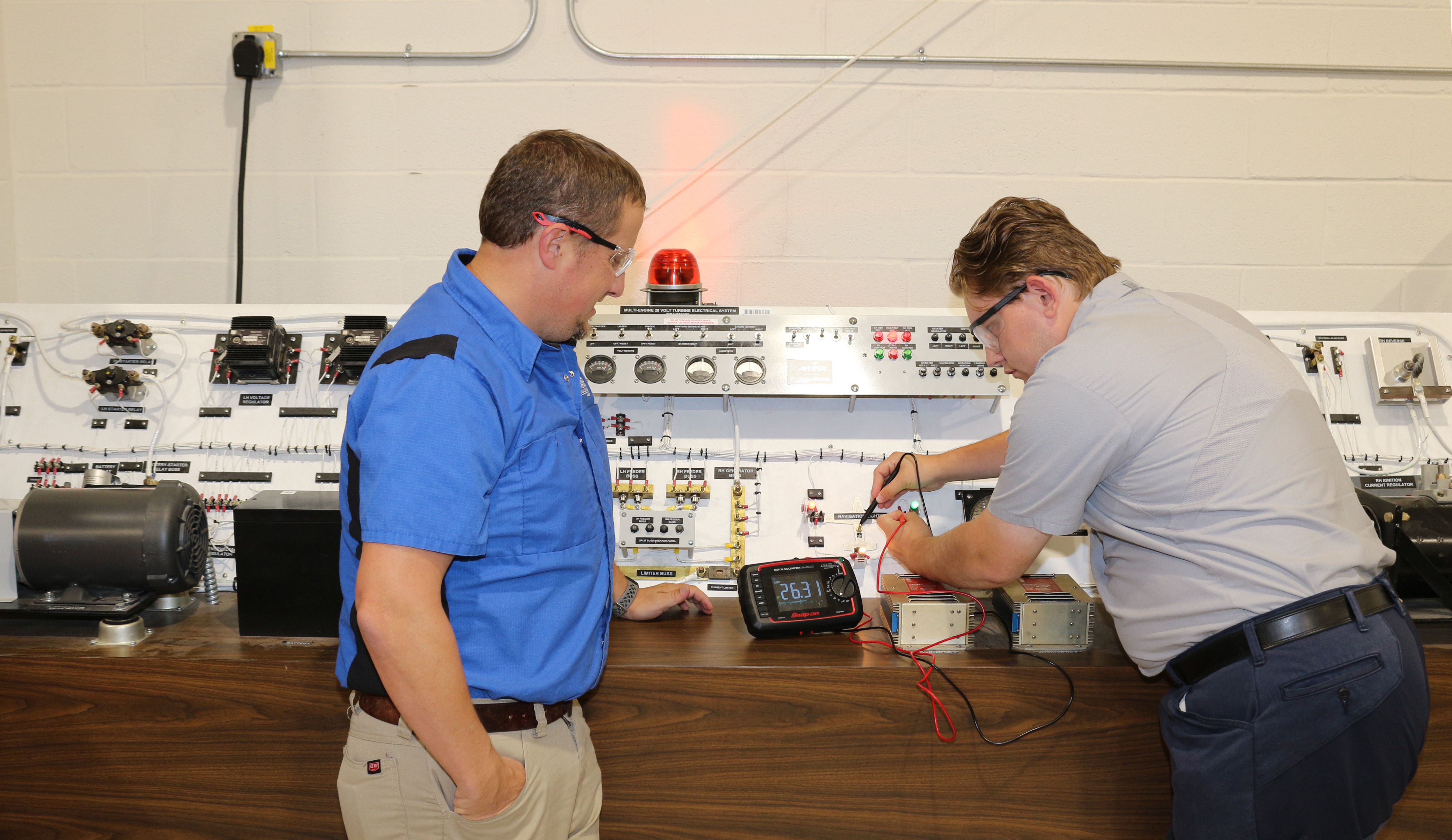 (From left) Zachary Fager, program director and instructor of Aviation Maintenance Technology, watches as Addison Talbot tests voltage using a Snap On Snap-on digital multimeter.